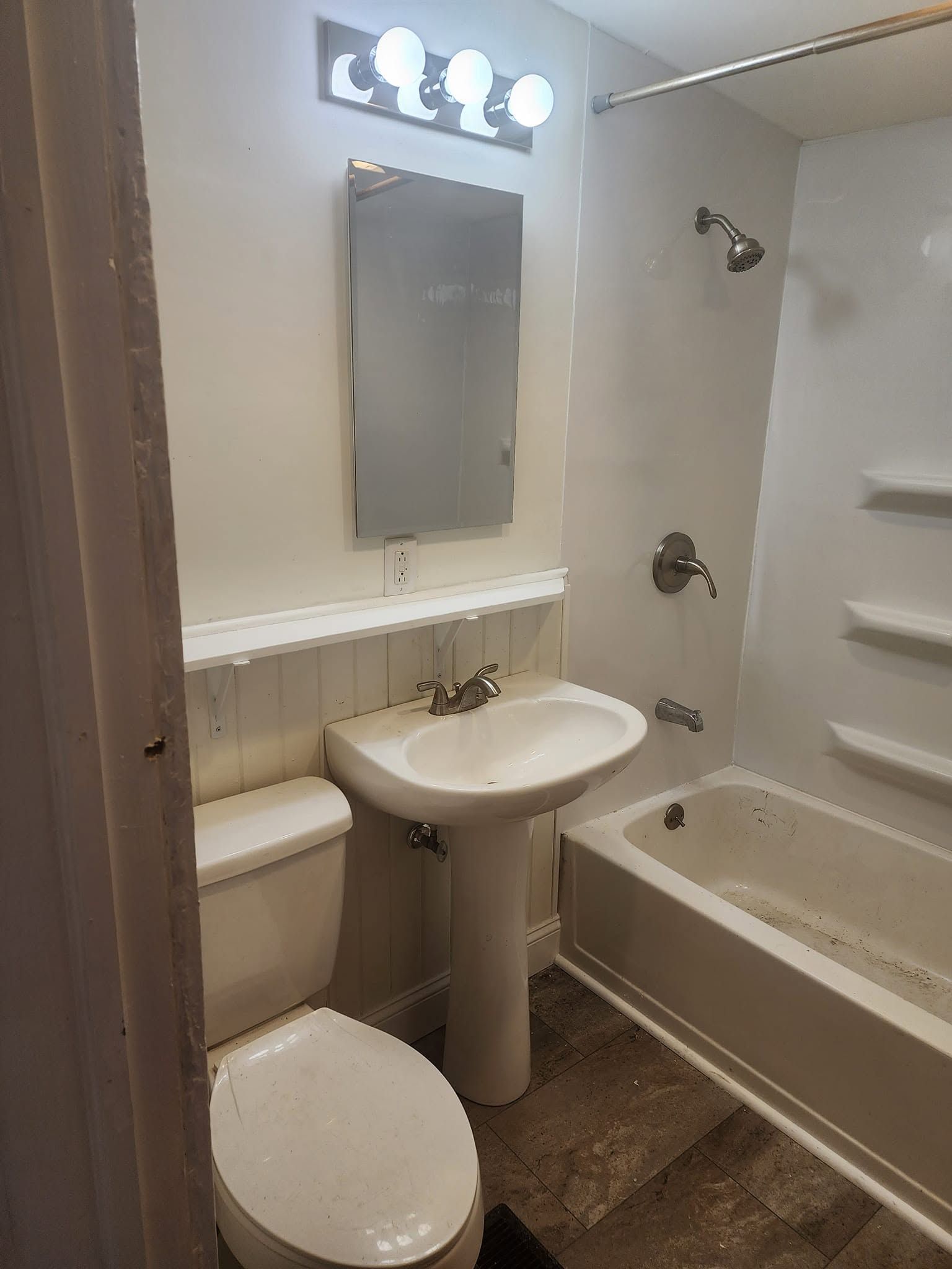 Small bathroom with toilet, pedestal sink, mirror, tub, and tan tile floor