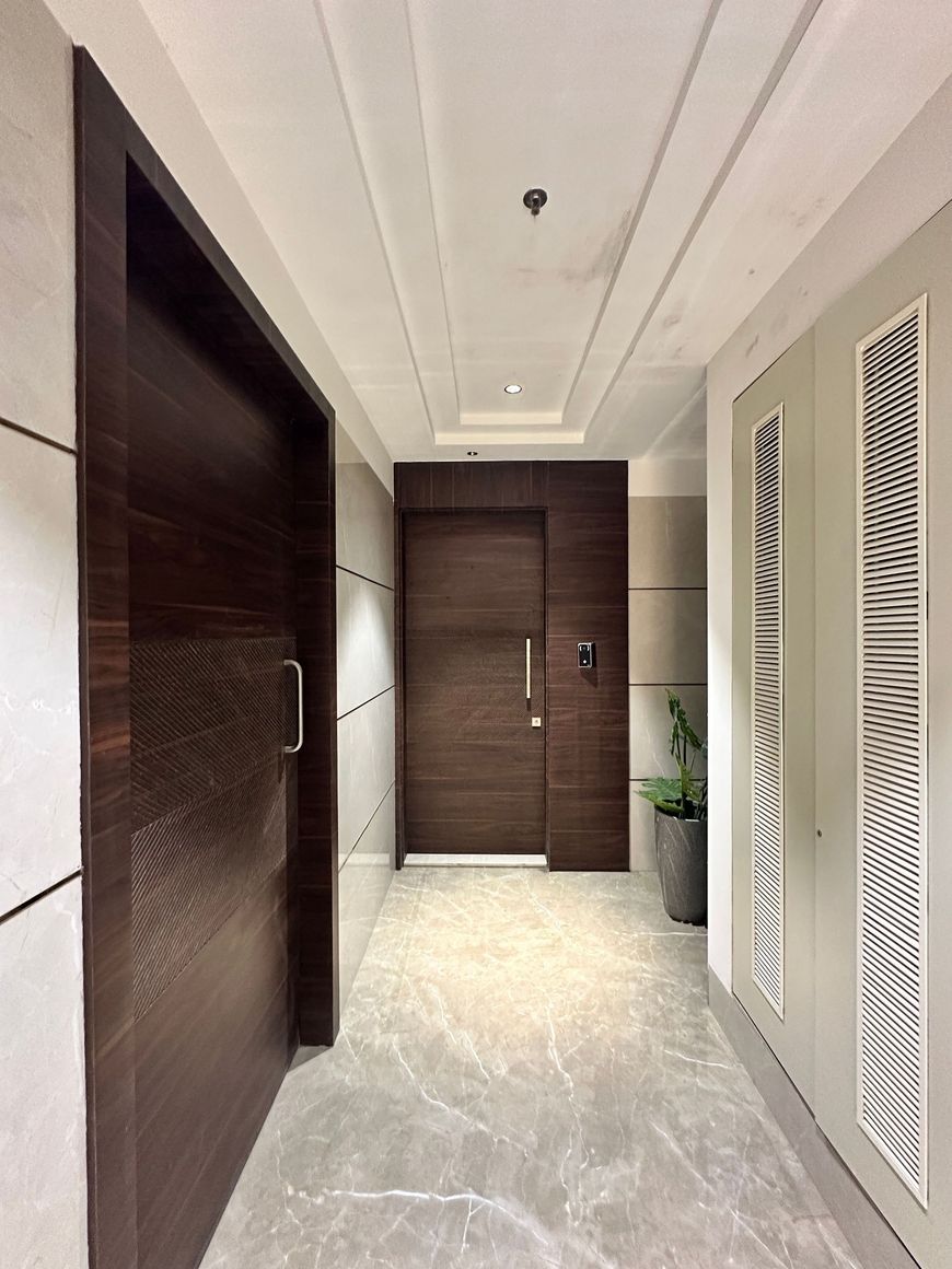 Modern hallway with dark wood doors, white walls, and light stone flooring