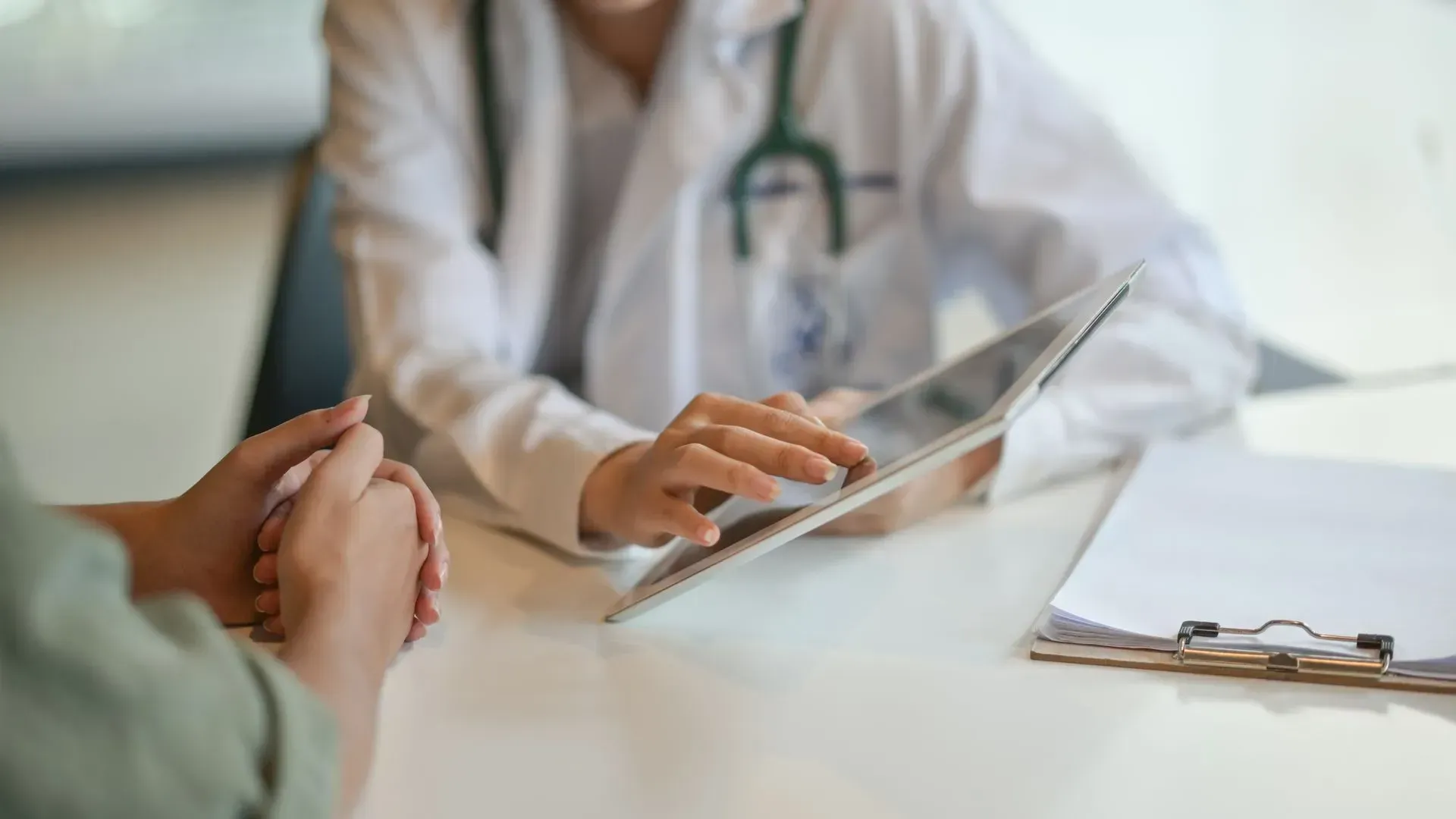 Doctor consulting with a patient over a tablet in a bright clinic office