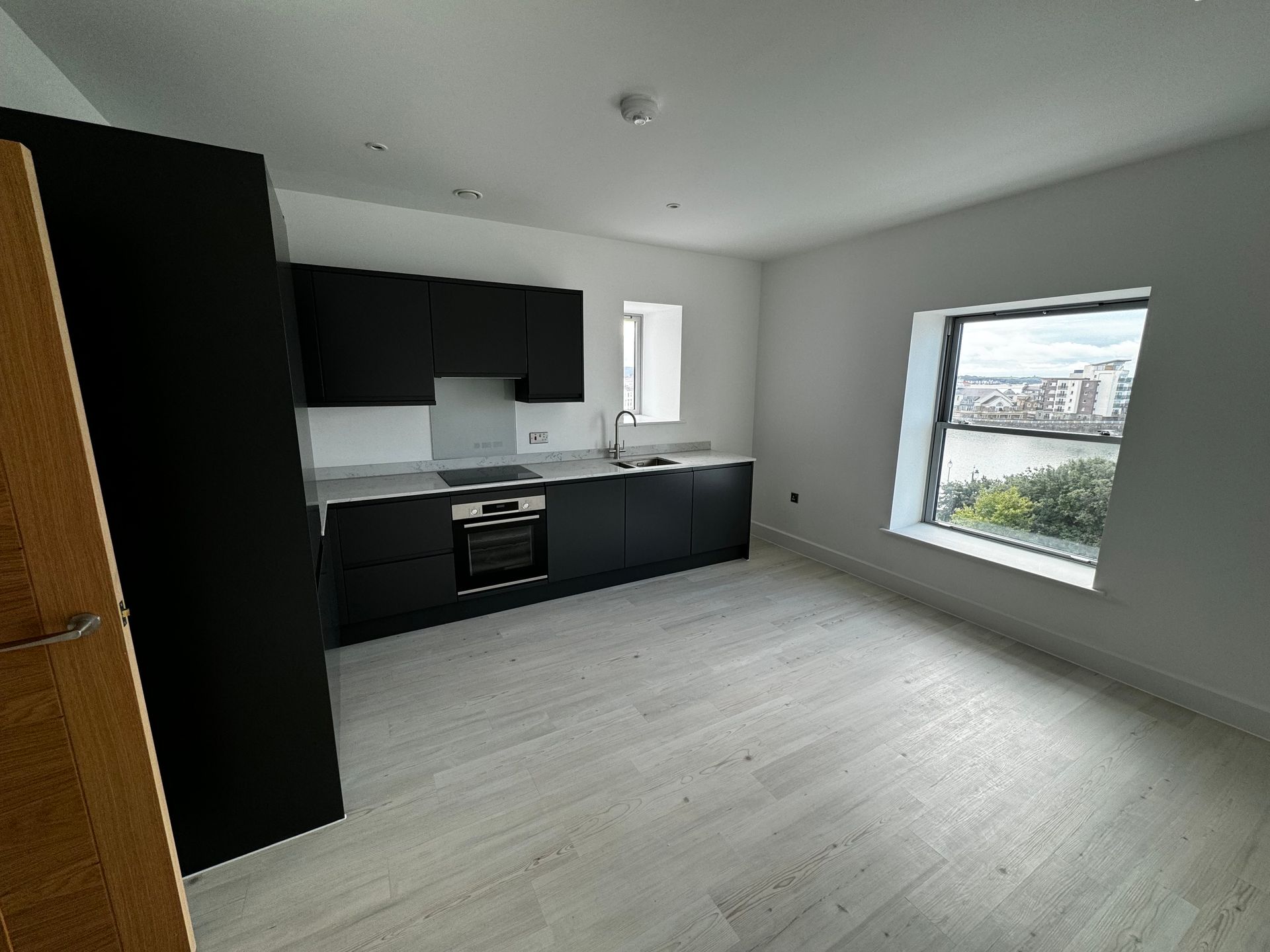 An empty kitchen with black cabinets and a window