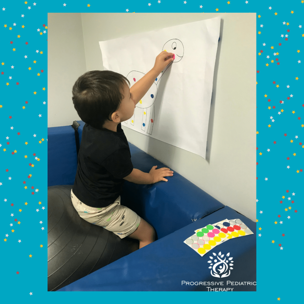 A young boy is drawing on a piece of paper on a wall.