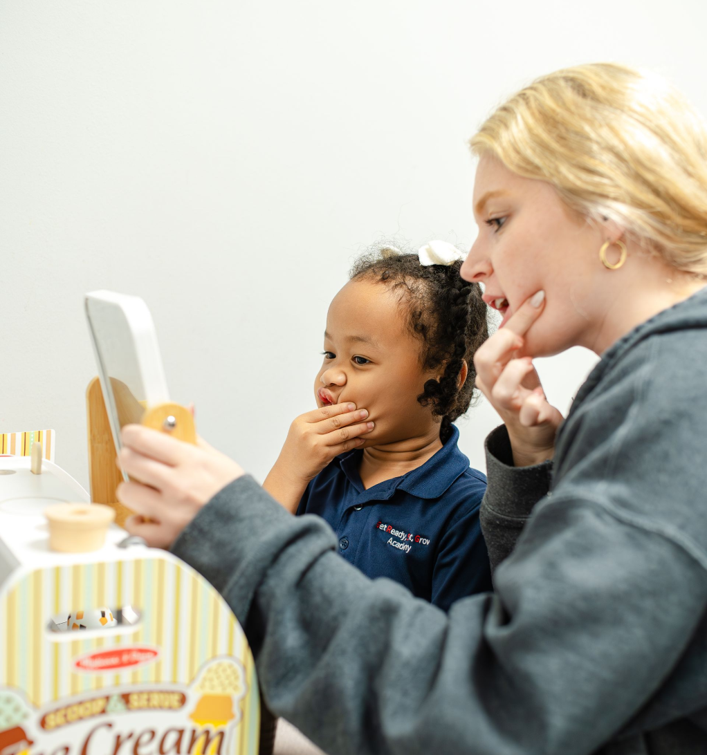 A little boy is sitting in a chair talking to a woman who is holding a clipboard