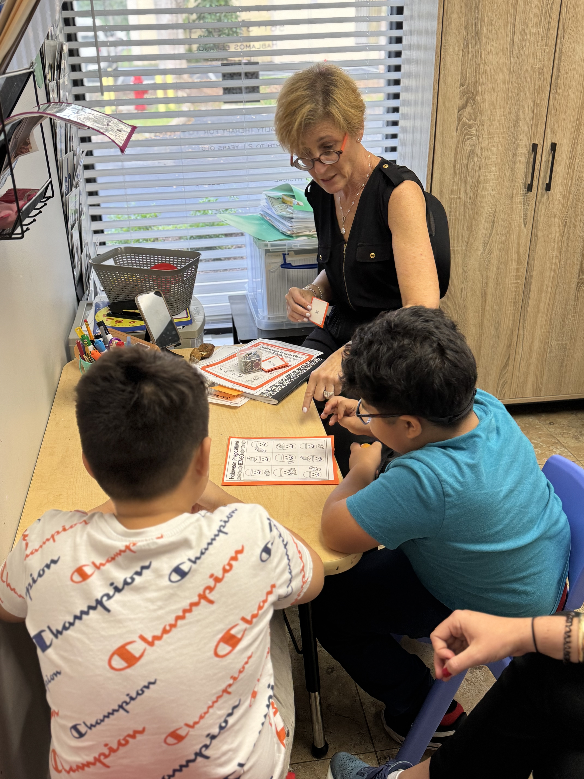 A woman is sitting at a table with two children.