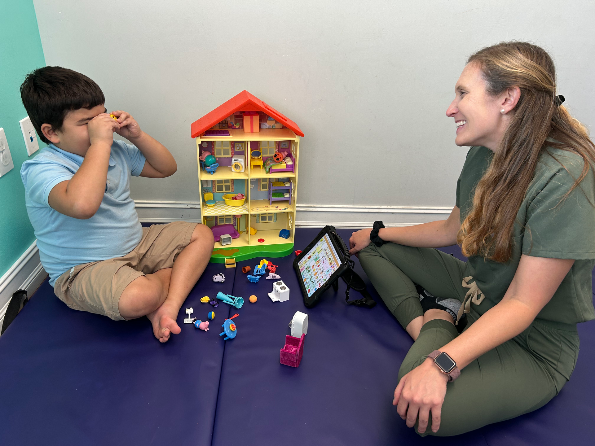 A woman is sitting on the floor next to a child playing with toys.