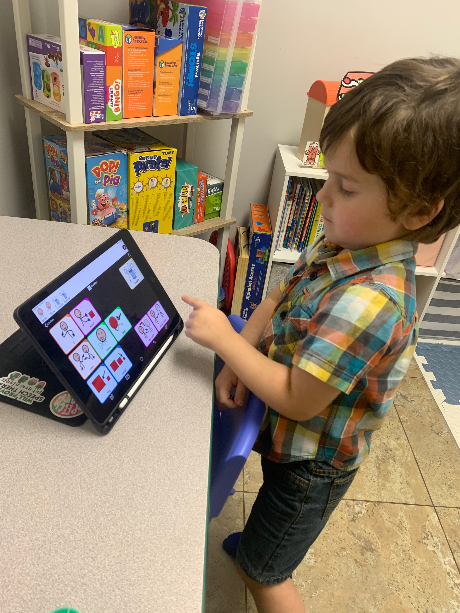 A young boy is standing in front of a tablet computer.