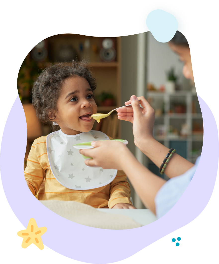 Child being fed with a spoon while seated in a high chair, wearing a bib in a cozy kitchen setting