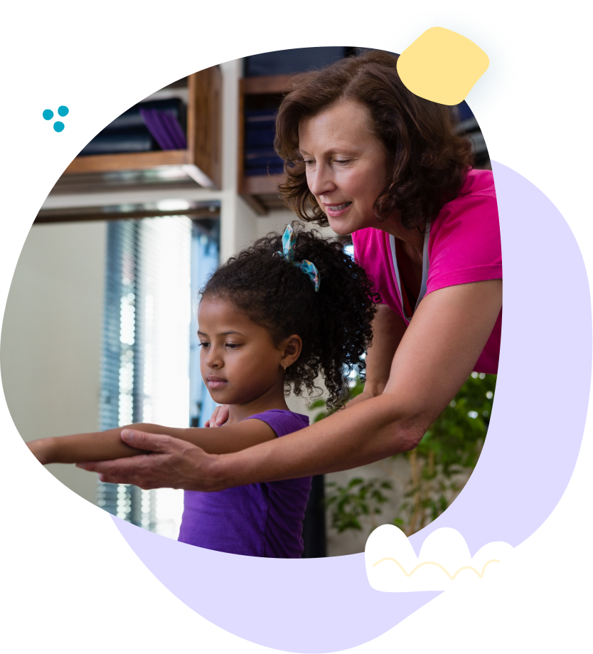A woman is helping a little girl stretch her arms.