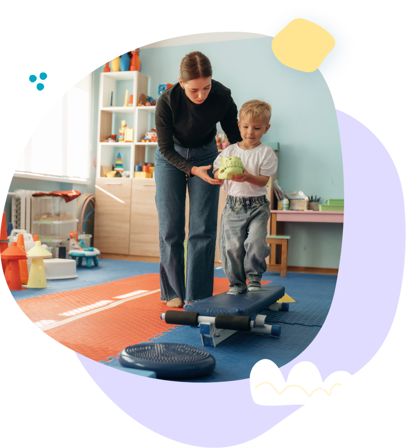 Adult helping child balance on a skateboard in a bright playroom