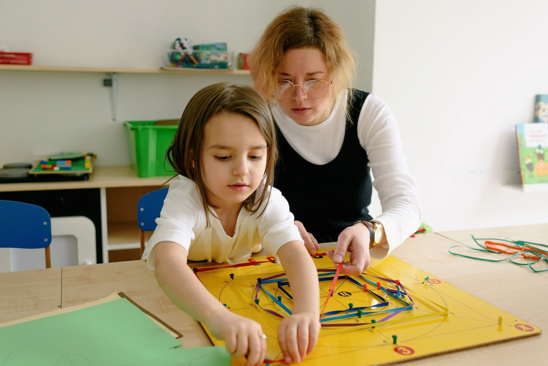 Adult and child arranging colorful pieces on a wooden activity board at a table