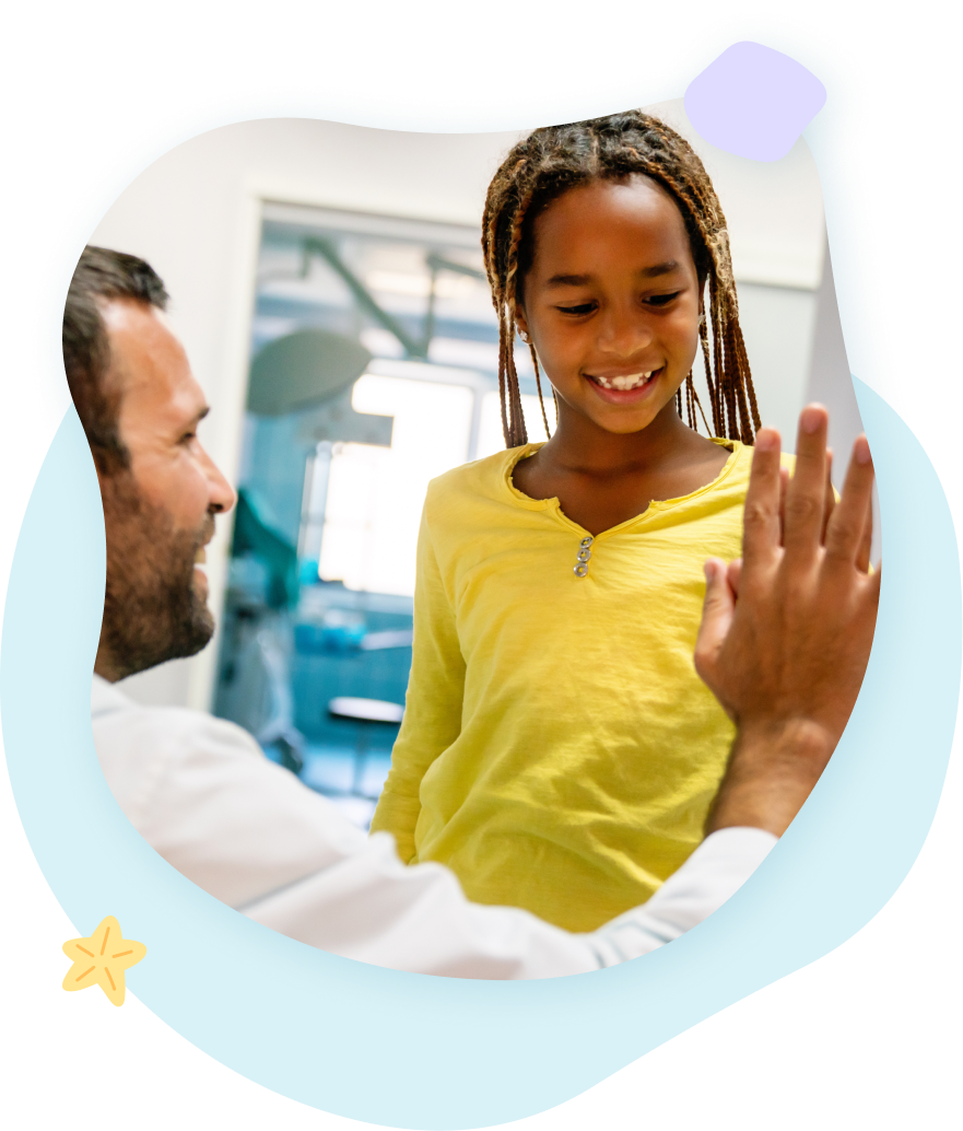 Man high-fives a girl in a medical setting; both are smiling. Yellow shirt, light blue background.