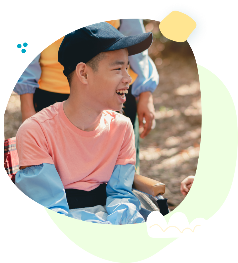 A young boy is sitting in a wheelchair and smiling.