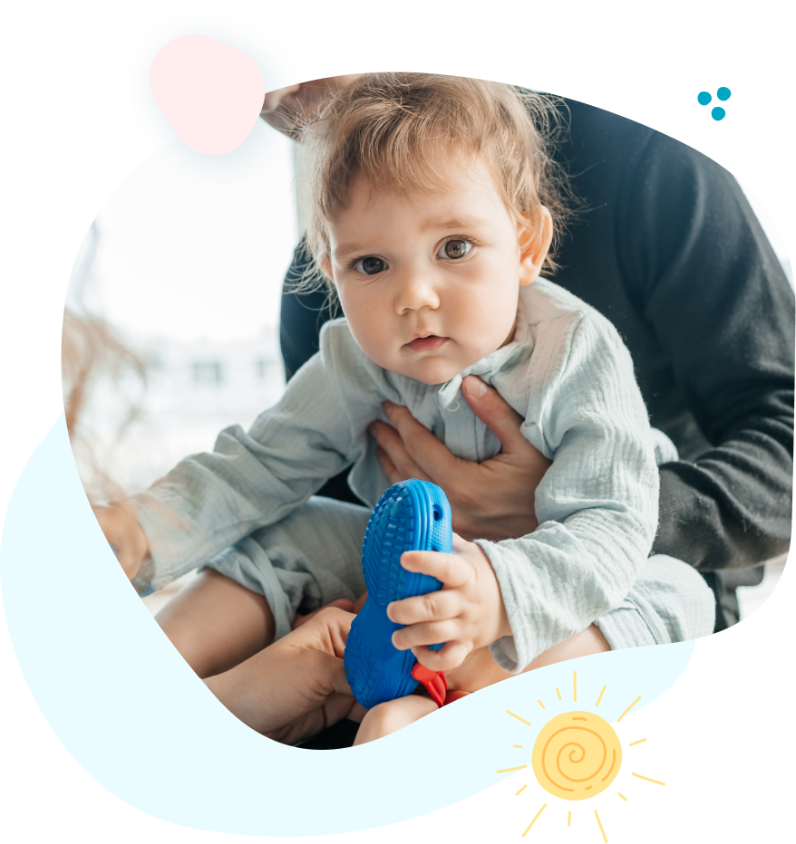 A baby is sitting on a man 's lap holding a toy.