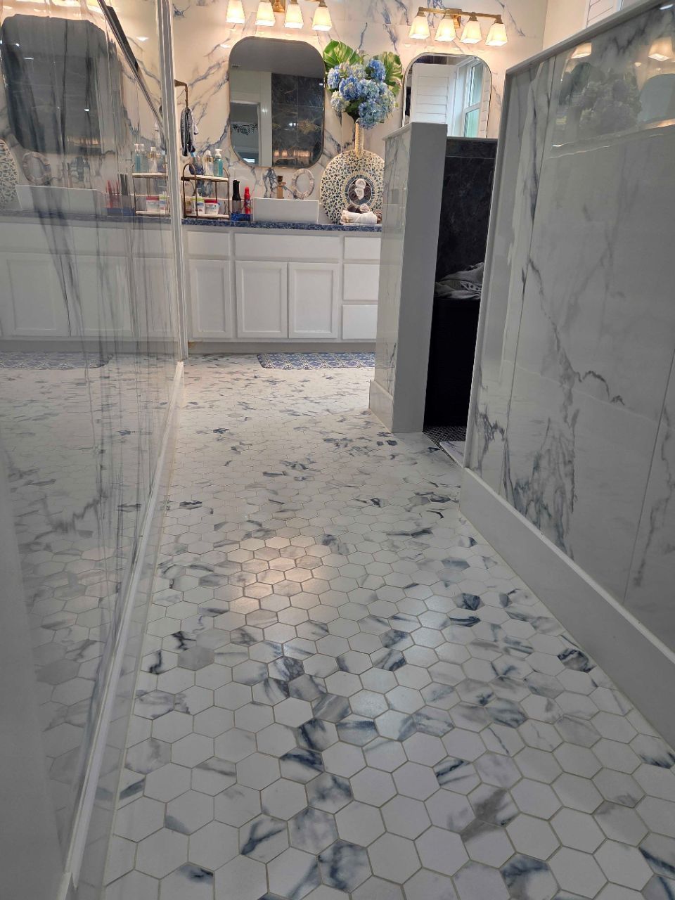 Marble-tiled hallway leading to a bright vanity room with ornate decor and a dark doorway on the right