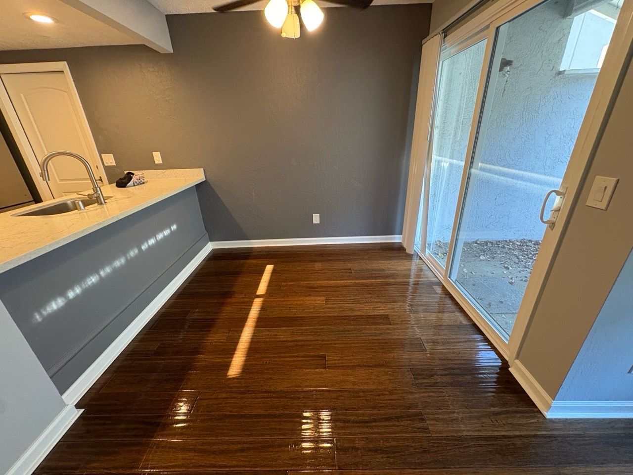Empty dining area with hardwood floor, gray walls, and sliding glass doors to a patio.