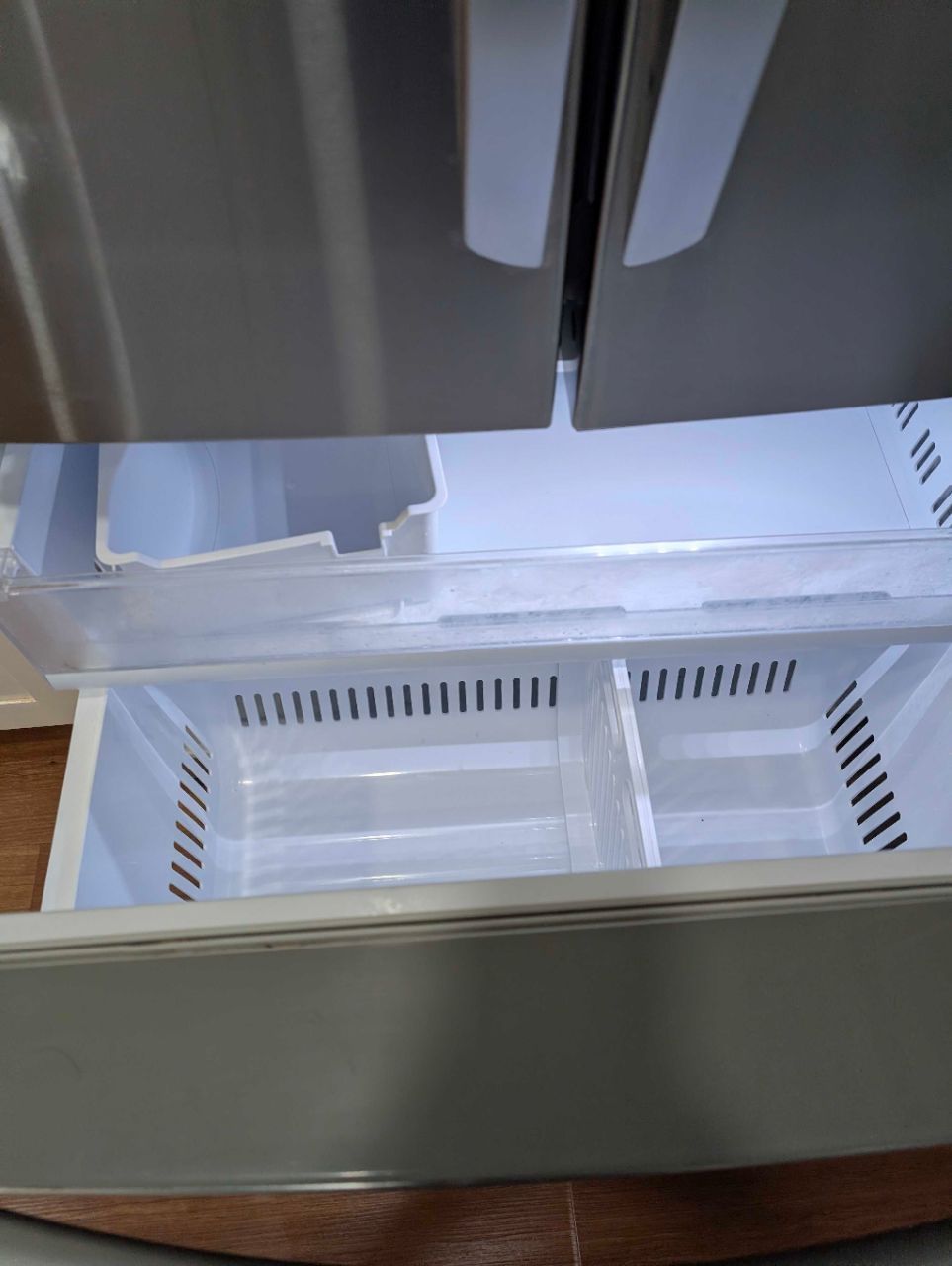 Open refrigerator with empty freezer drawer pulled out