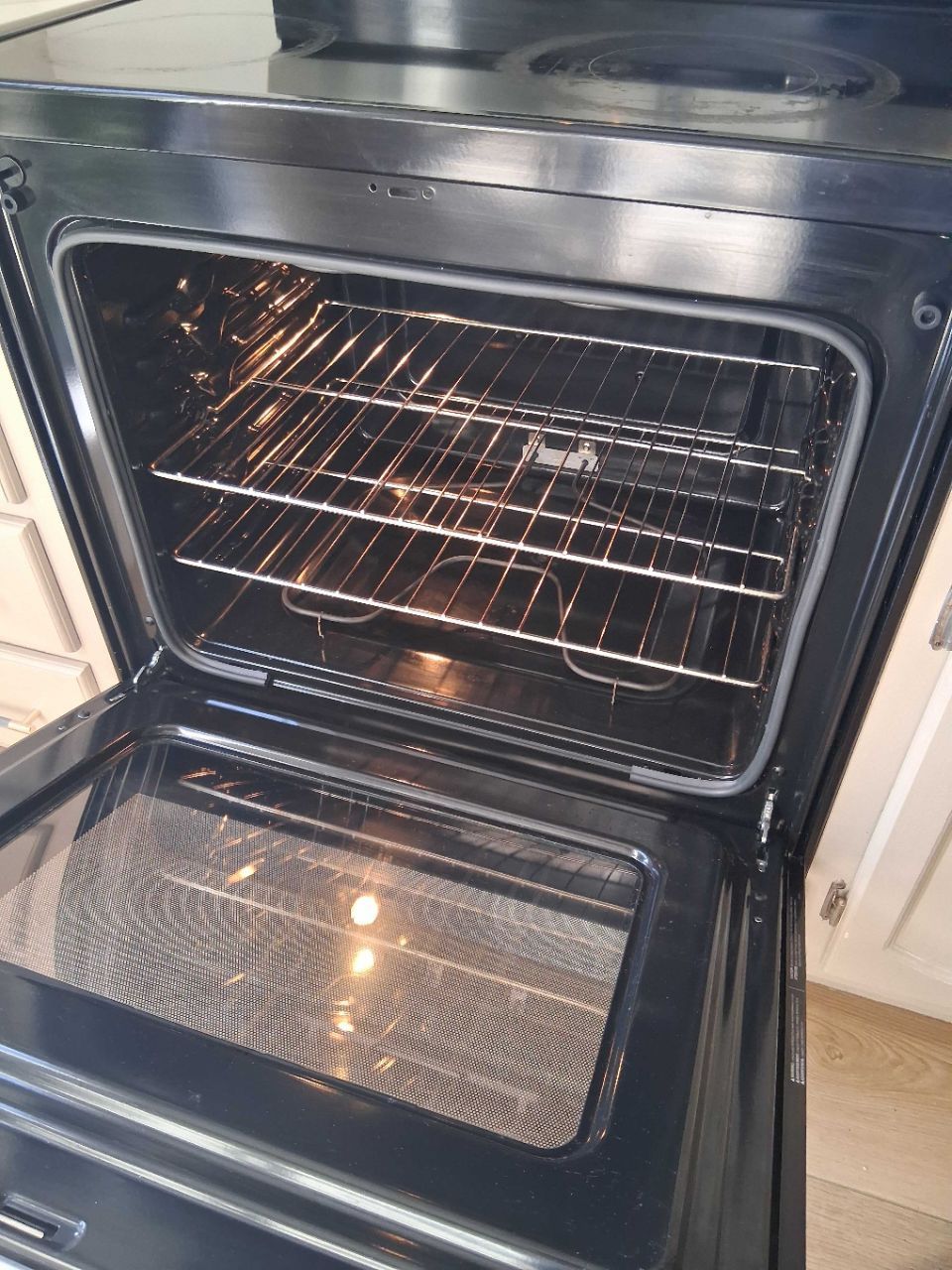 Open oven with empty wire racks and the door lowered open