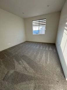 Empty carpeted room with white walls, a window, and closed closet doors.