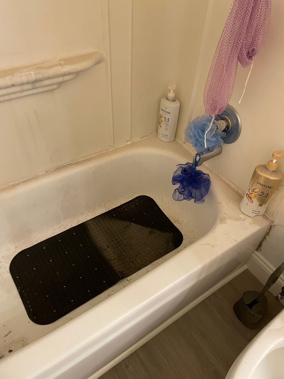Bathroom sink with a black basin insert, purple scrubber, and soap bottles on the counter