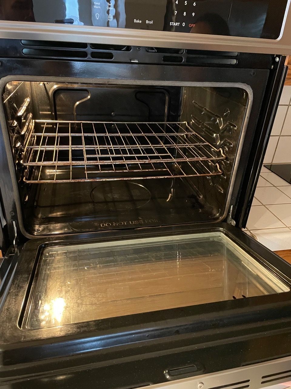 Open oven with wire racks and glass door in a kitchen.