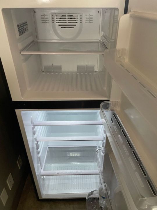 Open empty refrigerator with shelves and clear drawers visible inside