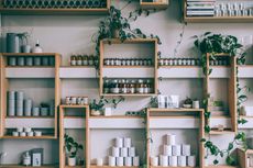 Wooden shelves with jars, tins, and plants in a bright minimalist kitchen or shop display