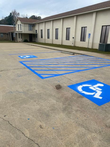 Accessible parking spaces painted blue in a lot beside a beige building