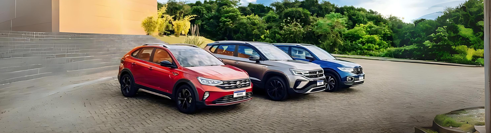 Três sedãs esportivos estacionados nas cores vermelha, prata e azul em um terreno de cascalho