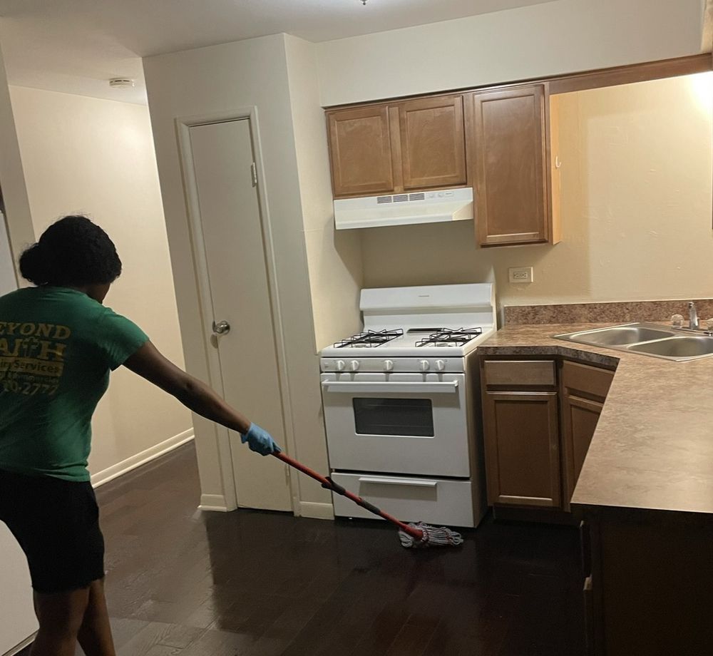 Person mopping a kitchen floor with white stove, wooden cabinets, and countertop.