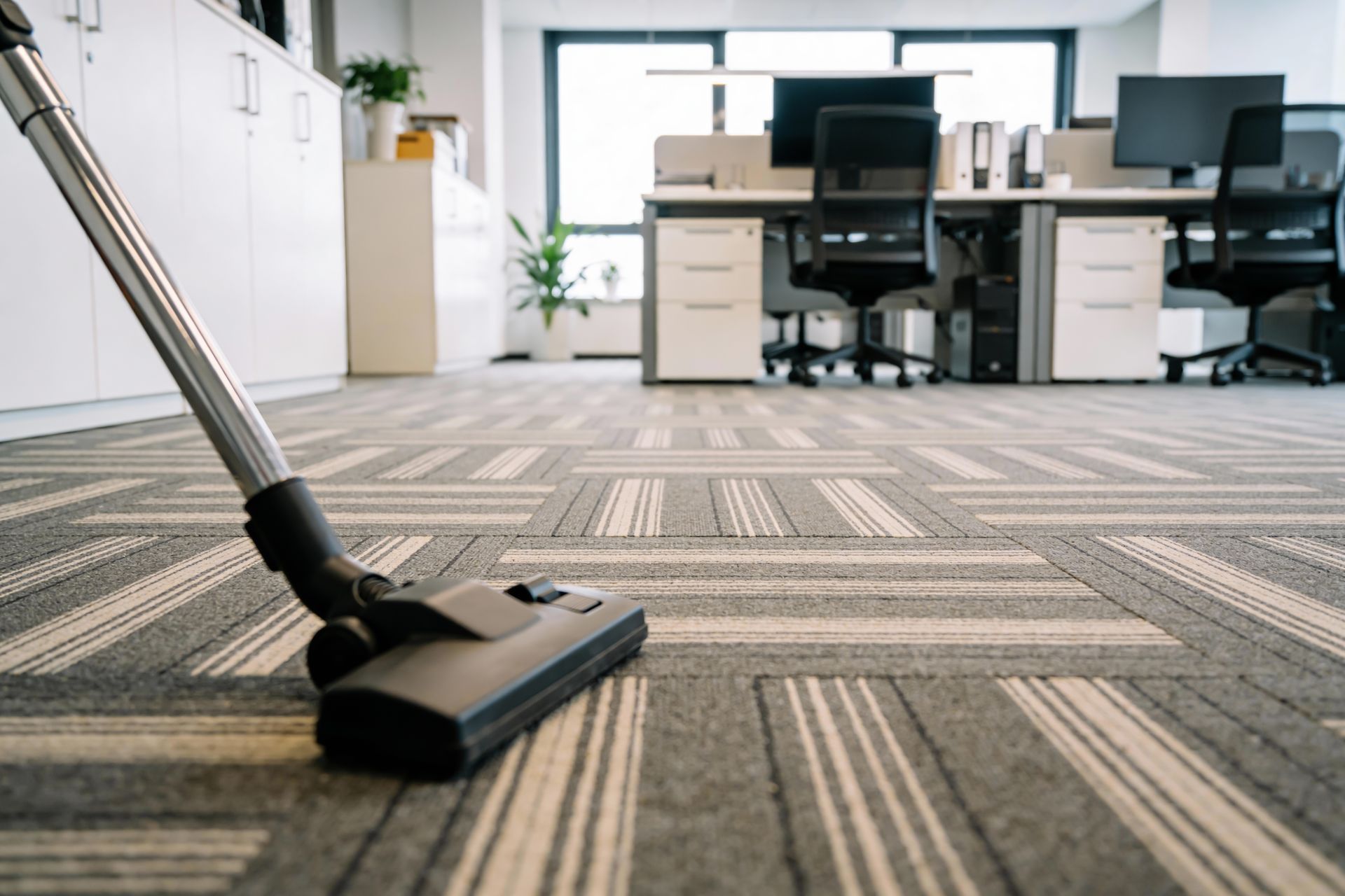 Vacuum cleaner on patterned office carpet in a bright open workspace