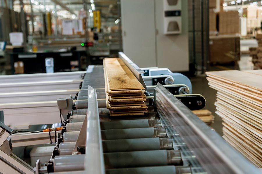 Nastro trasportatore che trasporta fogli di cartone impilati in una linea di produzione industriale.