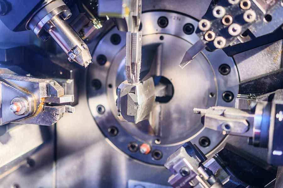 Macchine utensili robotizzate che modellano un componente metallico in un impianto di produzione industriale.