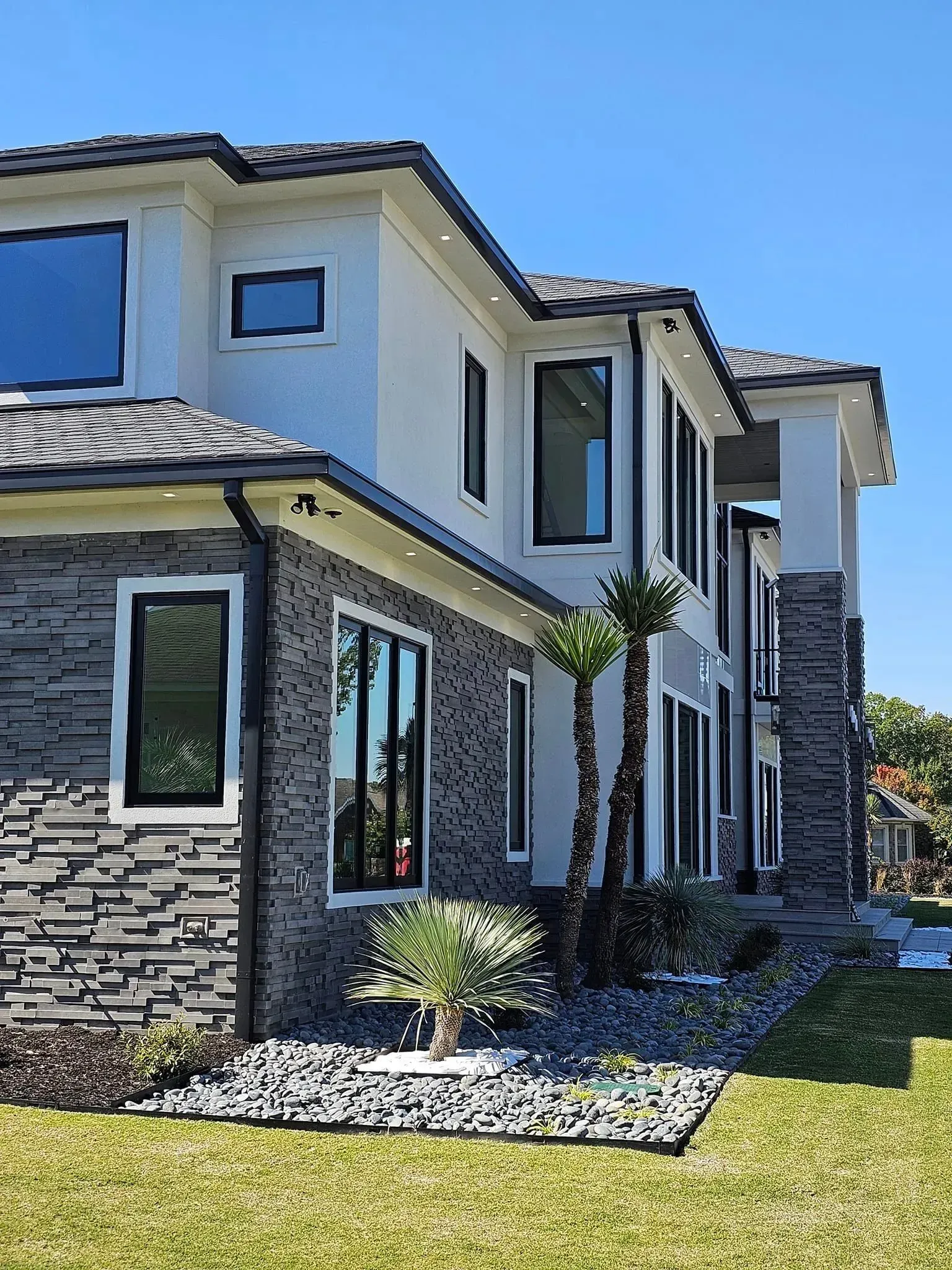 A large house with a lot of windows is sitting on top of a lush green lawn.