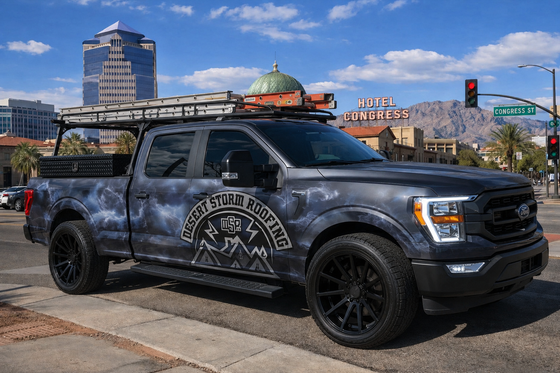 Black pickup truck with off-road tires parked by a city street and buildings in the background