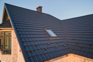 Dark blue tiled roof with a skylight on a house at dusk