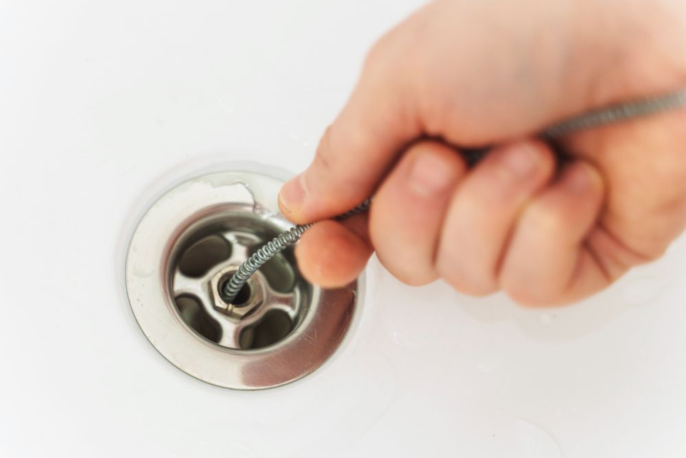 A Person is Cleaning a Sink Drain With a Brush — Dave's Plumbing and Gasfitting in Maroochydore, QLD