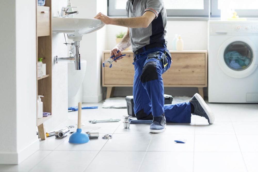 A Plumber is Fixing a Sink in a Bathroom — Dave's Plumbing and Gasfitting in Maroochydore, QLD