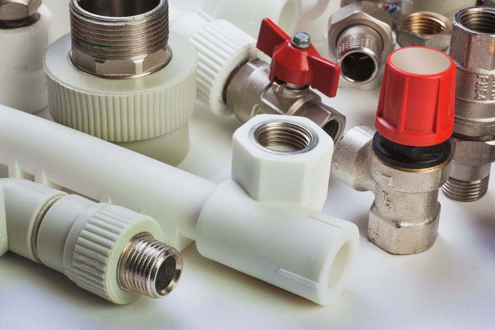 A Bunch of Plumbing Pipes and Valves on a White Surface — Dave's Plumbing and Gasfitting in Maroochydore, QLD