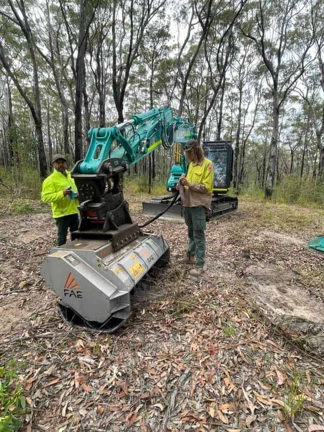 Two Men Standing Beside Excavator Scoop — Plant Operator Courses Central Coast 