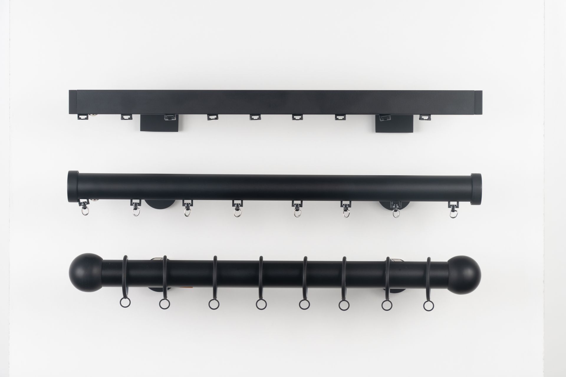 Three black drapery rods, each with hooks, on a white background.