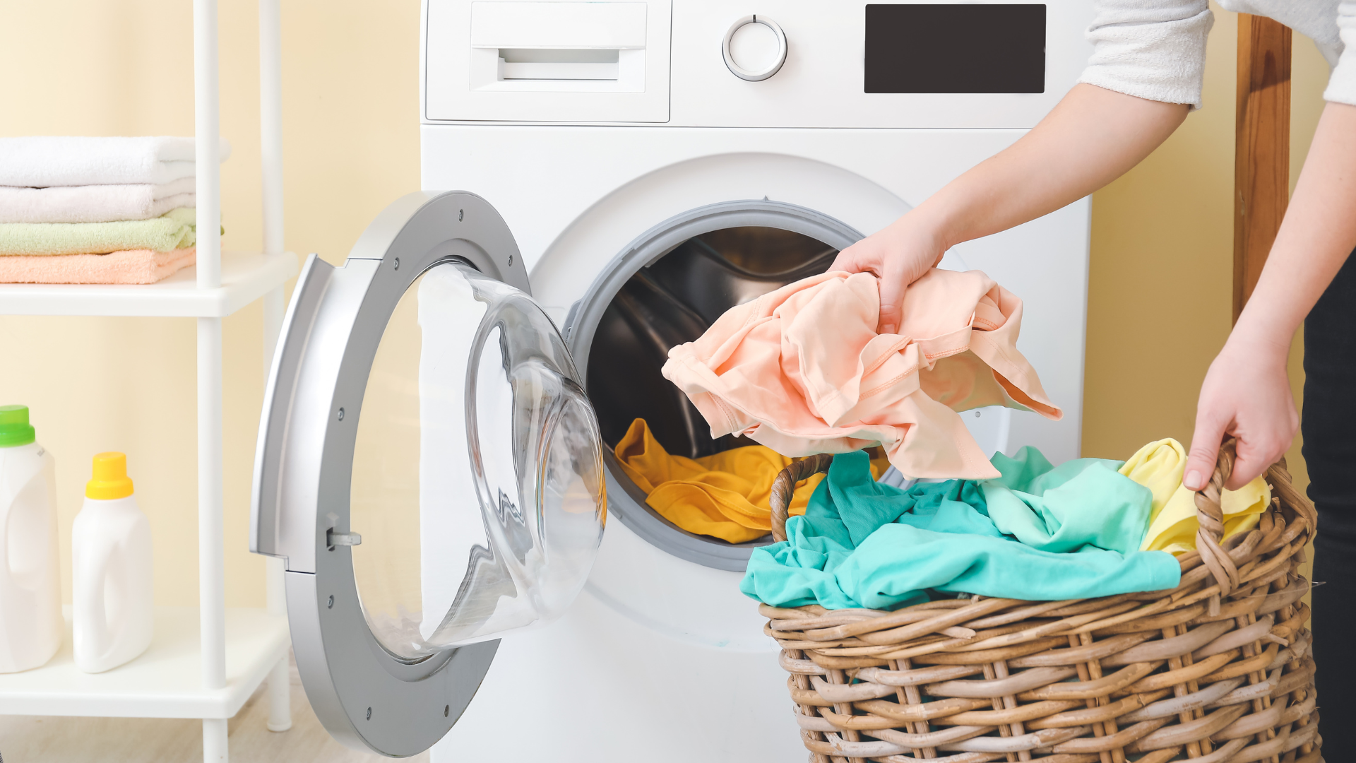 A person is putting clothes in a washing machine.