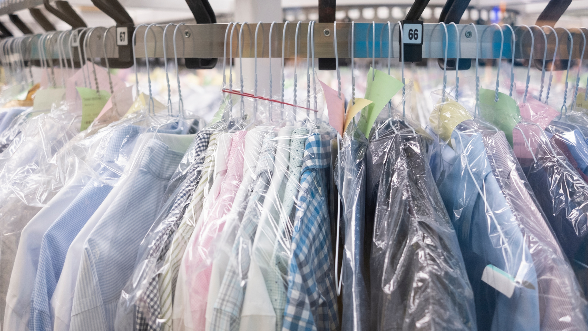 A bunch of shirts hanging on a rack in a dry cleaner.