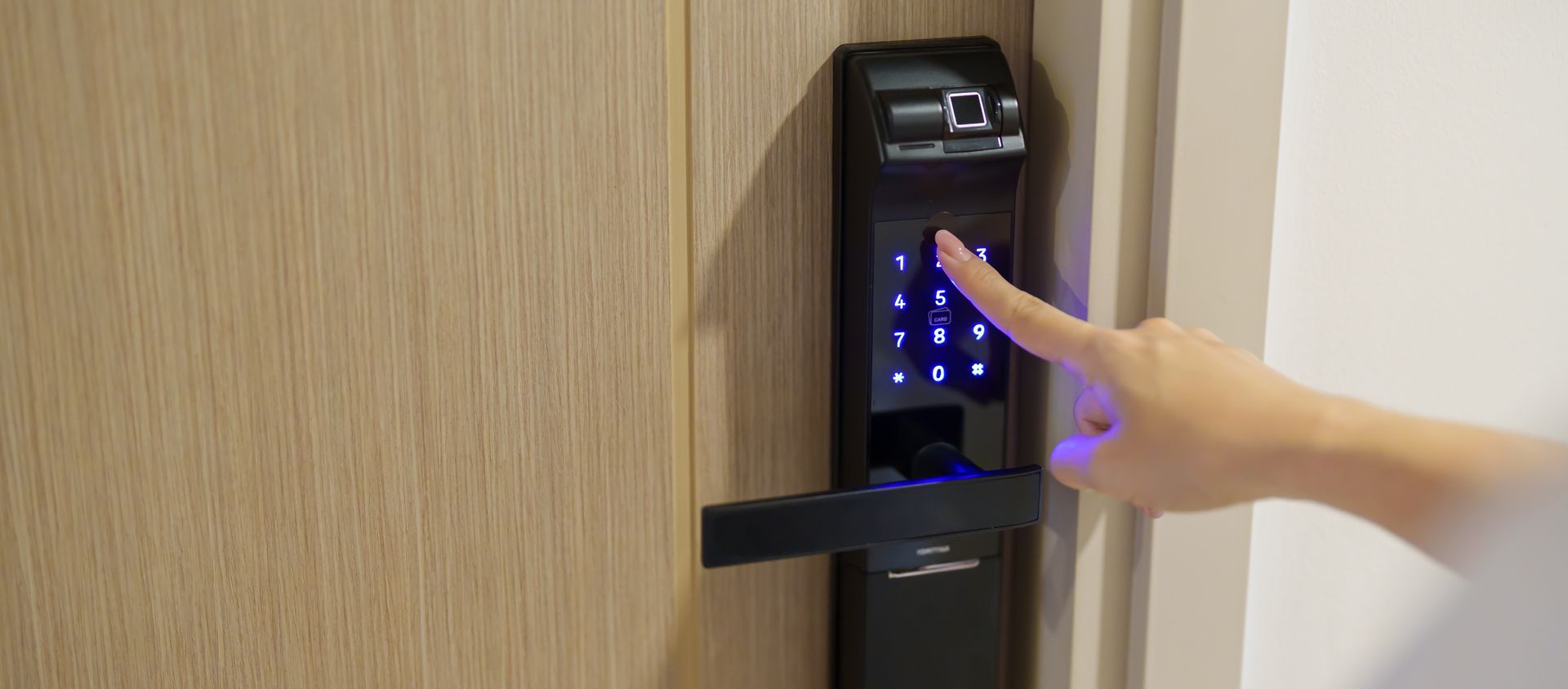 Person entering a PIN code on a smart door lock, showcasing modern access control systems.