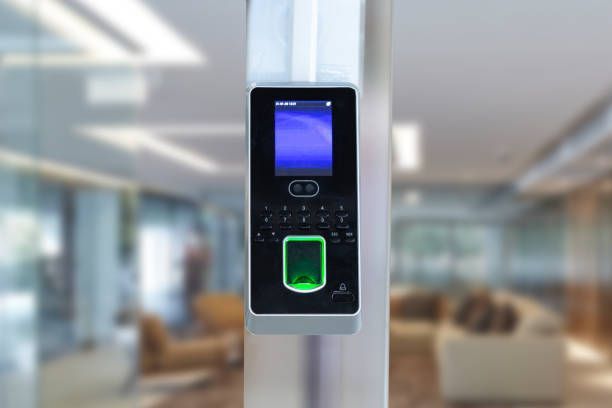 Biometric access control panel with screen and fingerprint scanner mounted on a pillar in an office lobby