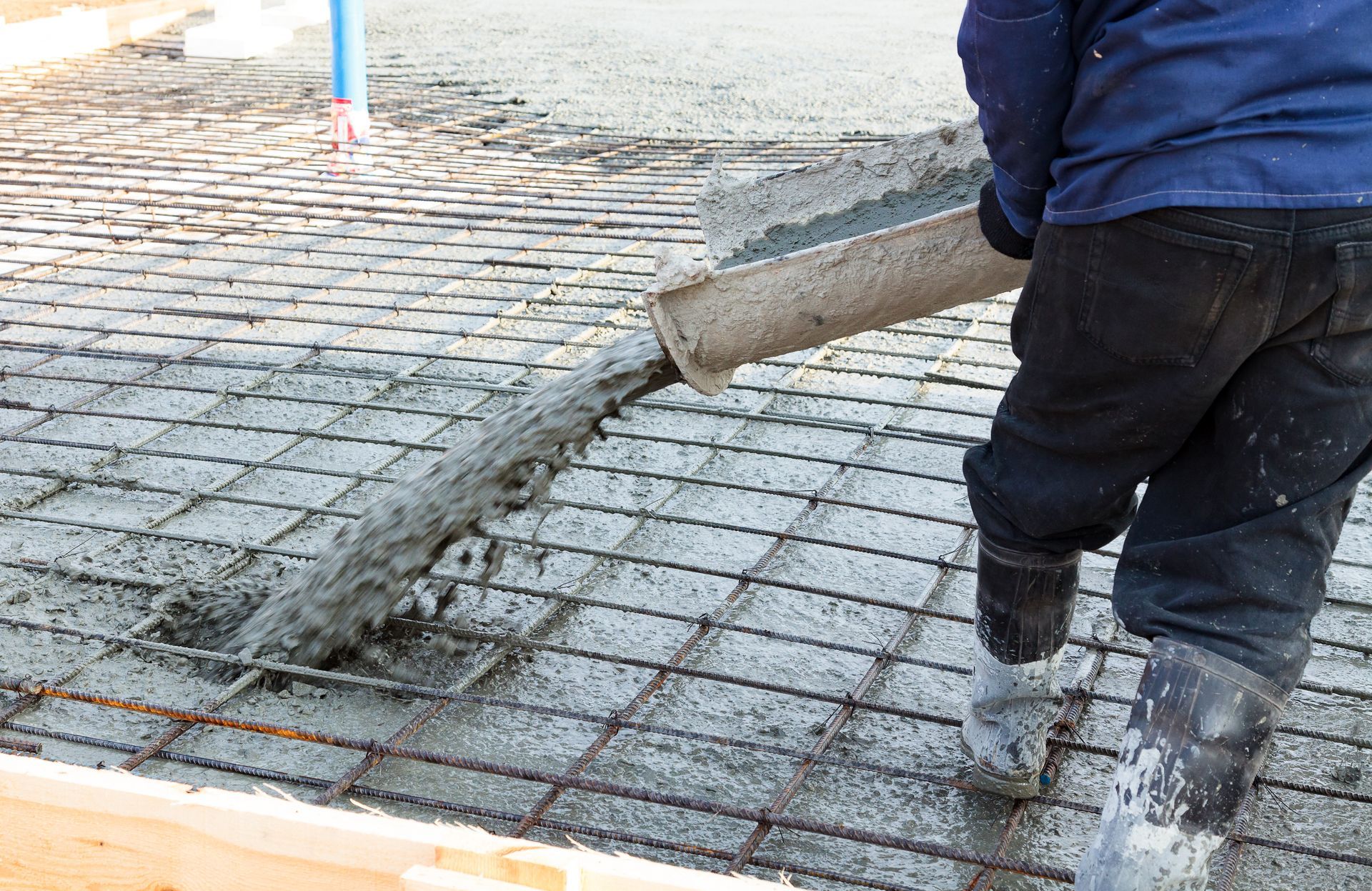 Une personne verse du béton dans un seau.
