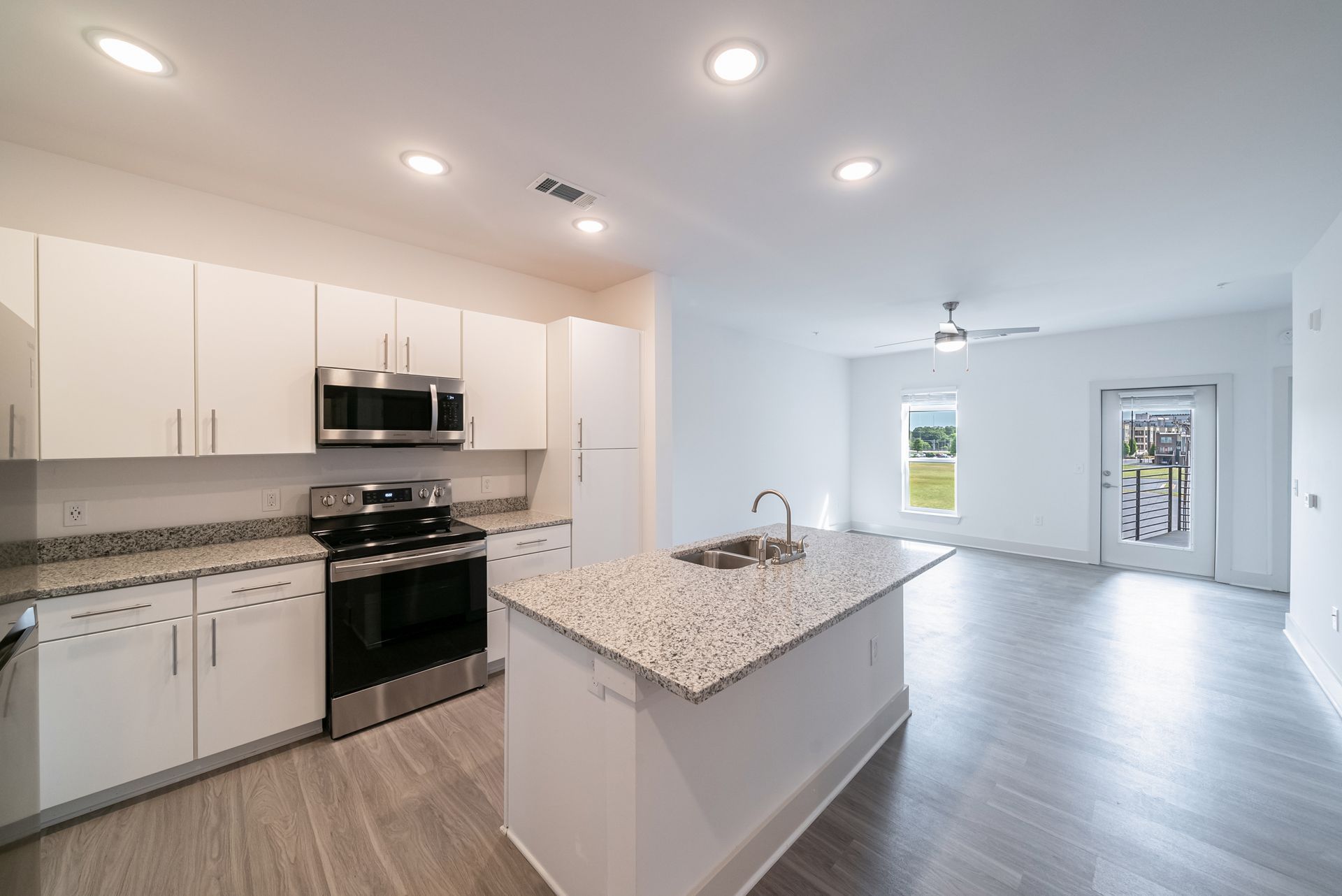 Modern kitchen with white cabinets, granite countertops, stainless steel appliances, and an island.