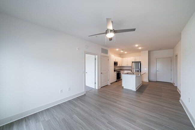 Modern apartment interior with light gray flooring, white walls, and open kitchen.