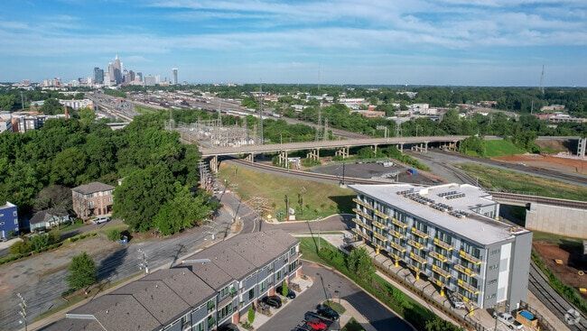 Aerial view of Charlotte, North Carolina, with a highway overpass, buildings, and the skyline in the distance.