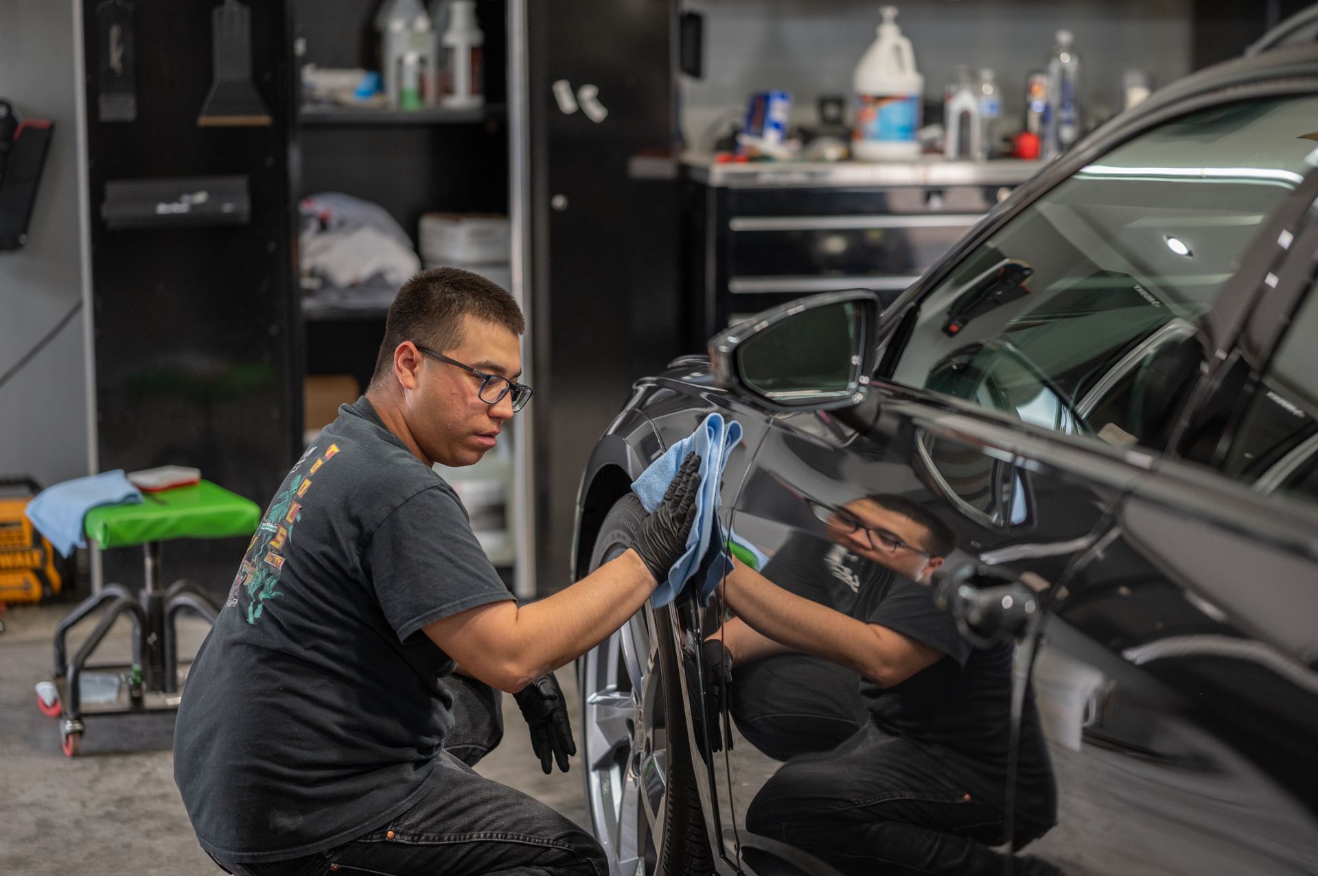 Detailing a black car with a blue cloth in a workshop garage