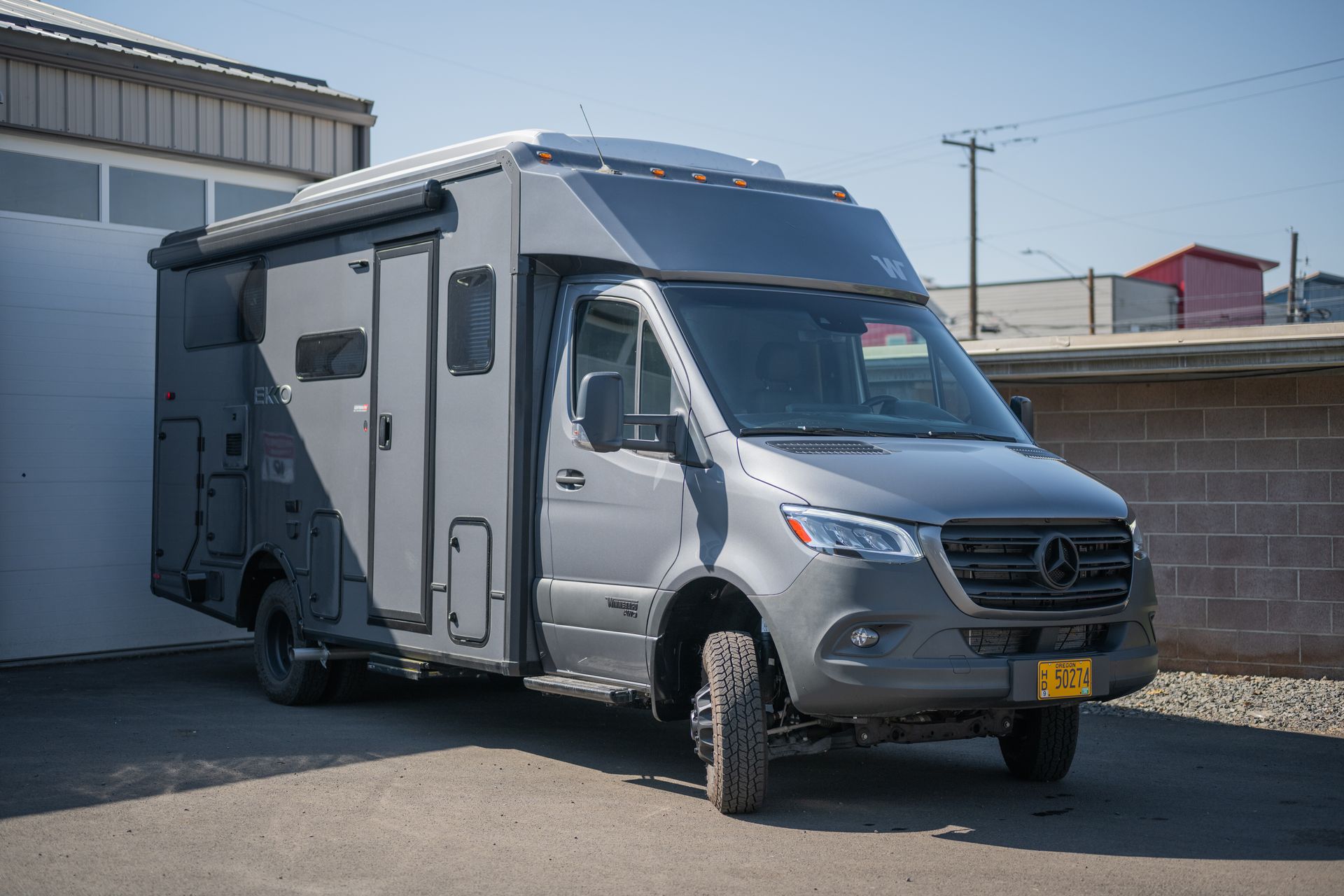 Silver camper van parked beside a building in an industrial lot