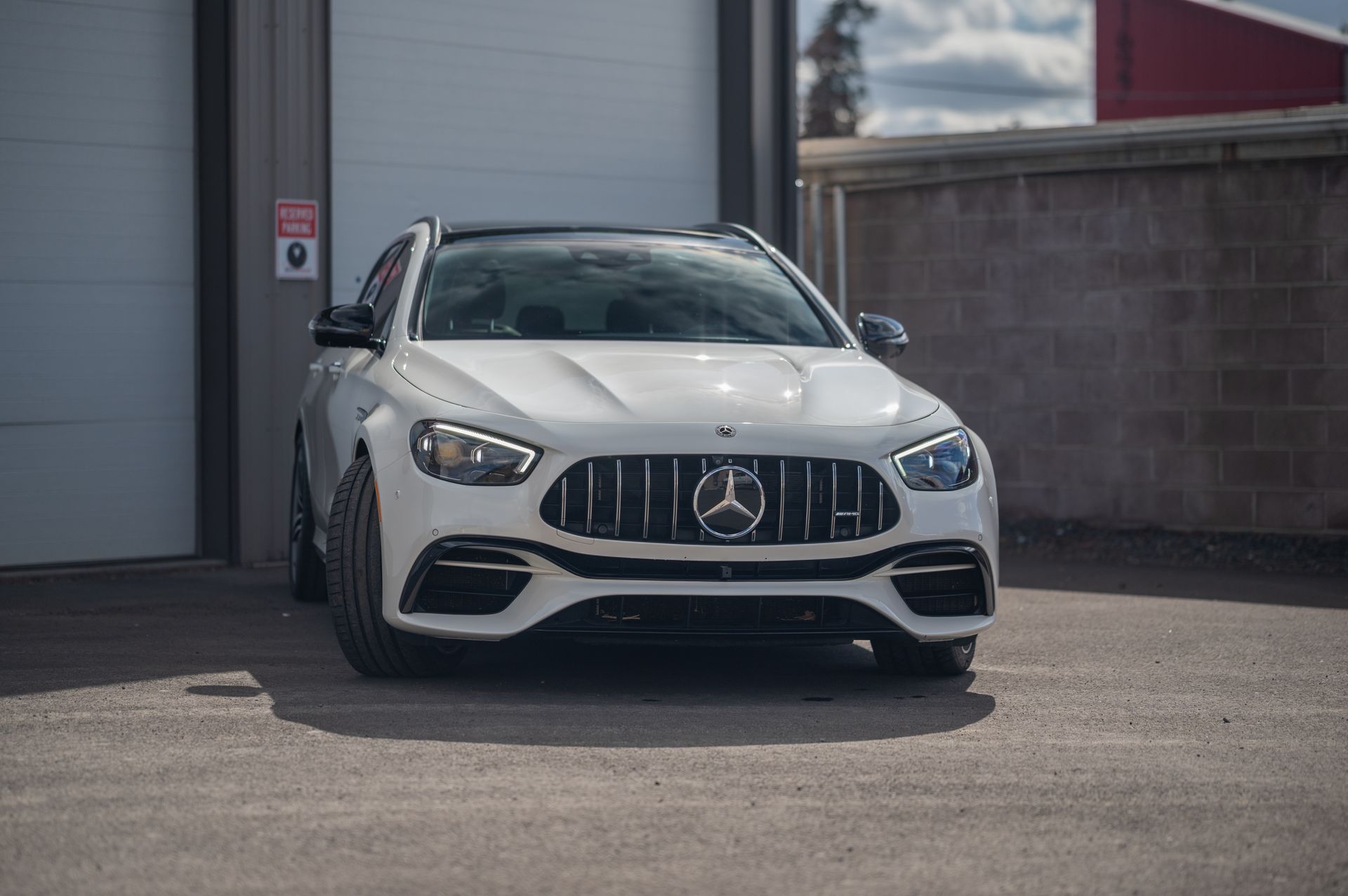 White Mercedes-Benz SUV parked outside a building, front view on pavement.